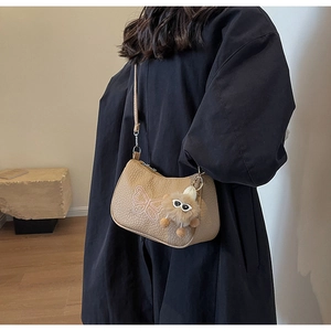 Détail du sac baguette kaki avec broderie papillon rose et breloque monstre en peluche