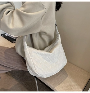 Detailed view of white quilted crescent bag with soft nylon texture and zipper