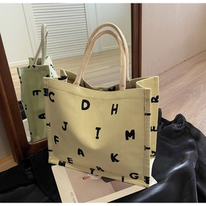 Detail of canvas tote bag with black letter print placed on elegant black satin fabric