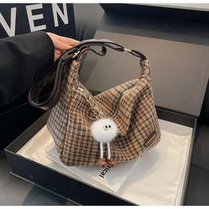 Détail du sac hobo en tweed à carreaux avec bandoulière en cuir et charm en peluche doux