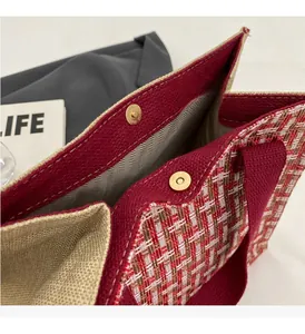 Detail of red checkered woven tote bag with golden magnetic snap closure and herringbone lining