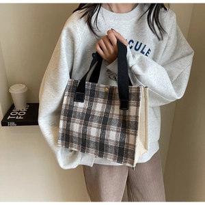 Détail d'un sac cabas rétro à carreaux en toile texturée avec des poignées noires