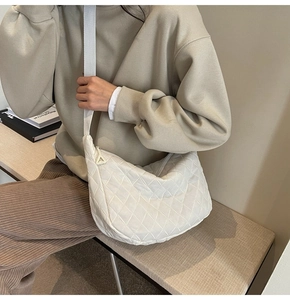 Detail of white quilted crossbody bag with adjustable strap and semi-circle cloud shape