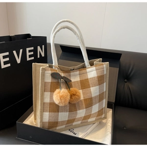 Detail of yellow checkered linen tote bag featuring woven rope handles and cherry pendant