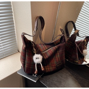 Détail du sac cabas en laine à carreaux rouge et marron avec breloque pompon et bandoulière