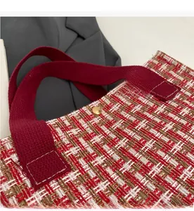 Detail of red tweed tote bag featuring woven texture and gold magnetic buckle closure