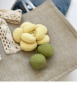 Detail of 3D fabric flower accessory with yellow petals on a linen tote bag