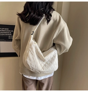 Rear view of a white quilted crossbody dumpling bag worn by a model in casual style