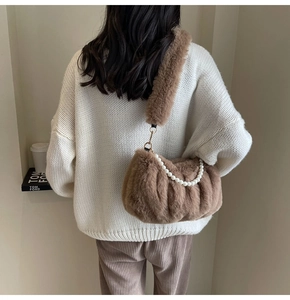 Detail of brown plush faux fur handbag featuring elegant pearl chain and soft texture