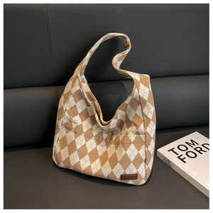 Detail of argyle pattern canvas shoulder bag on a sofa with fashion magazine decor