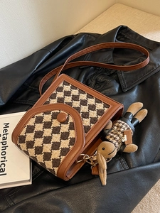 Chic checkered crossbody bag with leather trim and cute plush bunny charm on a jacket
