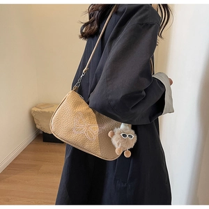 Vue détaillée du sac à bandoulière en cuir beige avec broderie papillon et breloque peluche