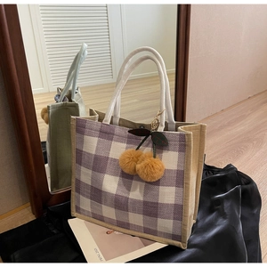 Detail of purple checkered linen tote bag with braided rope handles and cherry charm