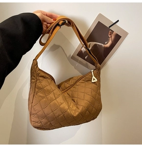 Detail of brown quilted hobo bag with nylon diamond pattern and triangle zipper