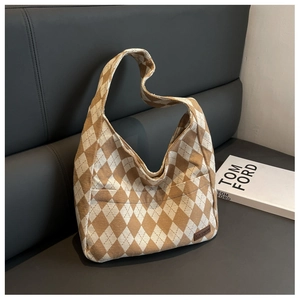 Detail of argyle knit tote bag with brown fashion patch on a grey leather sofa