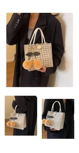 Detail of tweed tote bag with wooden button closure and cherry plush charm accessory