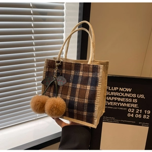 Detail of retro plaid lunch bag with plush cherry charm and durable canvas handle