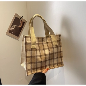 Détail d'un sac cabas à carreaux beige avec fermeture à bouton pression métallique