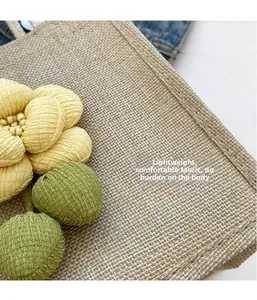 Detail of linen tote bag with yellow and green 3D flower decorations and fine stitching