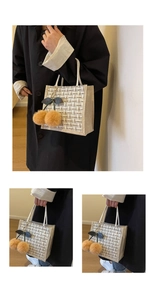 Detail of woven lattice tote bag with white rope handles and brown pom-pom cherry charm