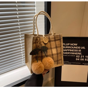 Detail of checkered burlap tote bag with cherry pendant and wood button closure