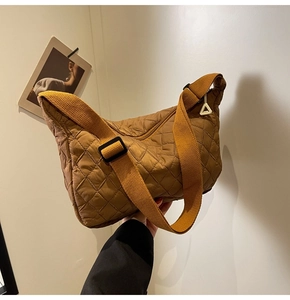 Detail of brown quilted crossbody bag with adjustable wide strap and unique zipper pull