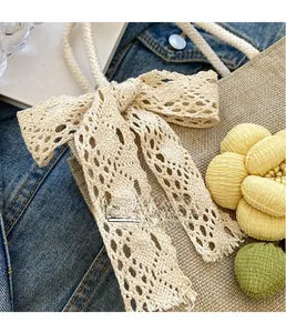 Detailed close-up of woven jute tote with beige lace bow and floral charm decorations