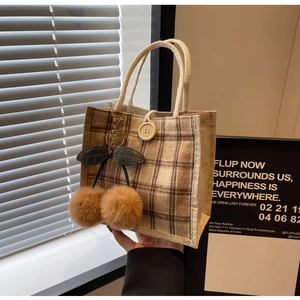Close-up of retro plaid handbag with cotton rope handle and cherry charm detail