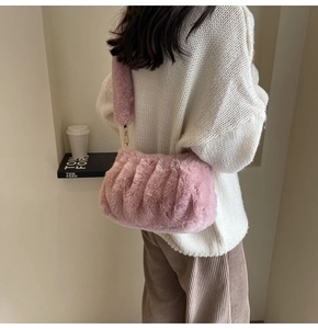 Detail of pink faux fur cloud bag with pleats and wide plush strap on a model