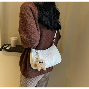 Détail du sac en cuir grainé blanc avec broderie papillon rose et pendentif en peluche