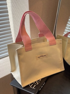 Sac fourre-tout en toile minimaliste avec anses roses posé sur un livre sous une lumière douce