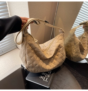 Detailed view of beige quilted crossbody bag with wide adjustable textile strap