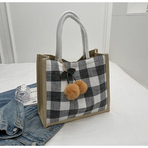 Detail of waffle plaid tote bag with woven rope handles and plush cherry charms