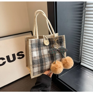 Close-up of checkered linen lunch bag with rope handles and cherry plush charm