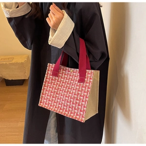 Detail of red and white woven tote bag with canvas side panels and gold snap button