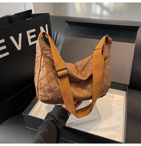 Detail of caramel quilted crescent bag featuring adjustable wide strap and nylon texture
