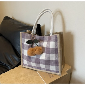 Close-up of waffle weave tote bag featuring purple checkered pattern and cherry pom pom