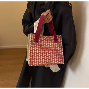 Detail of red tweed tote bag featuring woven pattern and reinforced webbing handles