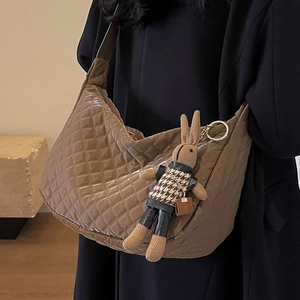 Sac hobo matelassé marron avec breloque lapin en tricot porté à l'épaule du modèle