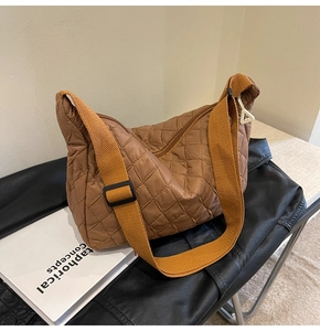 Detail of brown quilted nylon crossbody bag featuring diamond stitching and orange strap