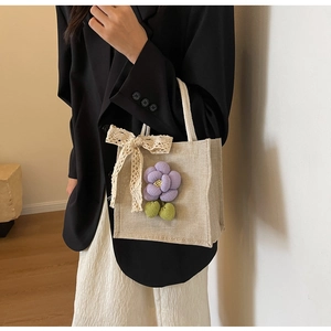 Detailed close-up of linen tote bag featuring 3D purple flower and lace bow decoration