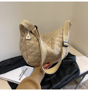 Detail of light khaki quilted crossbody bag featuring adjustable wide fabric shoulder strap
