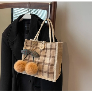 Detail of checkered tote bag with rope handle and orange cherry pom-pom accessory