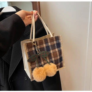 Detail showing the brown-blue checkered fabric and soft woven rope handle of the bag