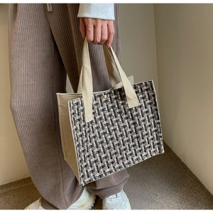 Close-up of a tweed tote bag with metal buckle closure and durable canvas handles
