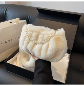 Close-up of white plush cloud bag with pearl chain decoration in luxury gift packaging