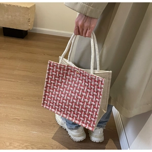 Detail of red and white woven tote bag with durable rope handles in a lifestyle setting