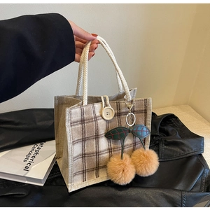 Detail of vintage plaid lunch bag with woven handle, wooden button and cherry charm