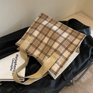 Sac cabas rétro à carreaux avec poignées tissées brunes et fermoir métallique sur un blouson