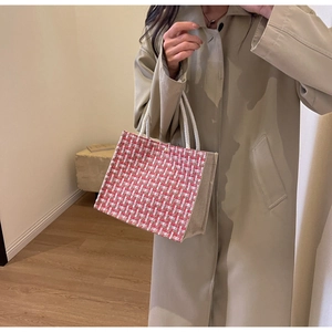 Detail of red and brown woven tote bag with cotton rope handles and metal fastener